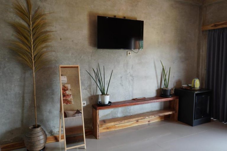 Habitación del Tasola Boutique Hotel con televisor en pared, banco de madera y plantas decorativas