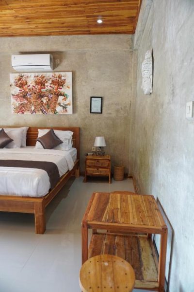 Habitación doble con cama de madera, techo de bambú y decoración balinesa en Tasola Boutique Hotel