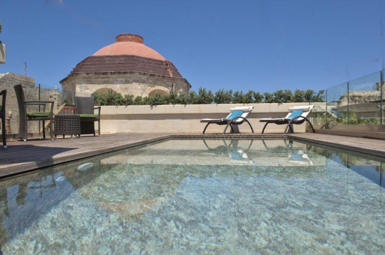 Piscina exterior en terraza con tumbonas y cúpula histórica del Palazzo Consiglia IK Collection en Malta