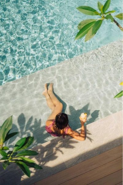 Mujer relajándose al borde de la piscina con cóctel en el hotel Amari by Vivere Hospitality Group