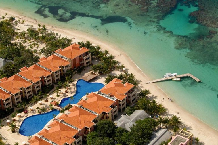 Vista aérea del Infinity Bay Spa & Beach Resort con piscinas, muelle privado y playa de arena blanca