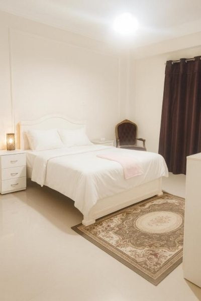 Habitación doble con cama matrimonial blanca y alfombra clásica en Hotel Laguna King Care & Comfort