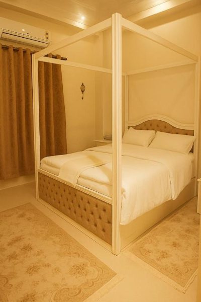 Habitación de lujo con cama de dosel blanca y tapizado capitoné en Hotel Laguna King Care & Comfort