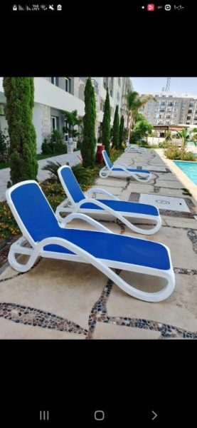 Tumbonas azules y blancas junto a la piscina exterior de la Aldea Fanadeer Bay en Hurghada
