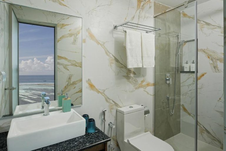 Baño de mármol con ducha acristalada y vista al océano en el hotel H78 Guraidhoo Maldivas