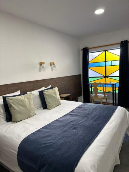 Habitación doble con cama king size y vidriera decorativa en Hotel FK Paso de los Toros Boutique
