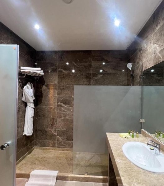 Baño de lujo con ducha de mármol oscuro y amenities en el Hotel Royal Mirage Deluxe
