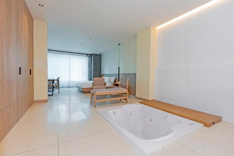 Suite del Iconik Hotel con bañera de hidromasaje integrada en la habitación y zona de descanso
