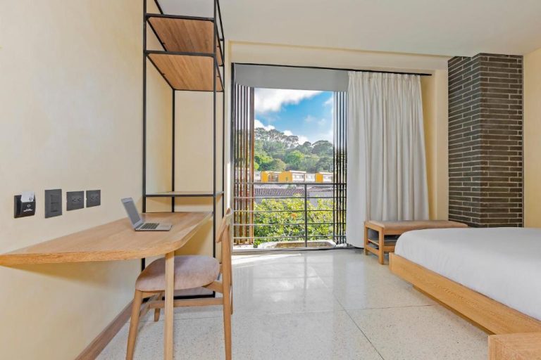 Habitación moderna con escritorio de madera, balcón y vista exterior en Iconik Hotel