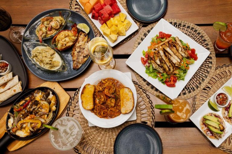 Variada selección de platos del restaurante Puerta Azul con mariscos, pasta, ensalada y frutas frescas