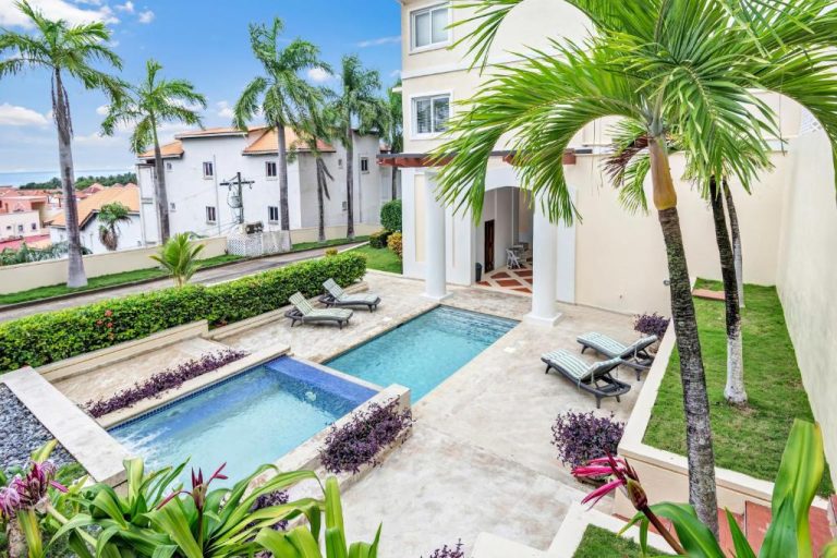 Piscina exterior con jacuzzi y tumbonas rodeada de palmeras en Sea Vue Luxury Vacation Condominiums