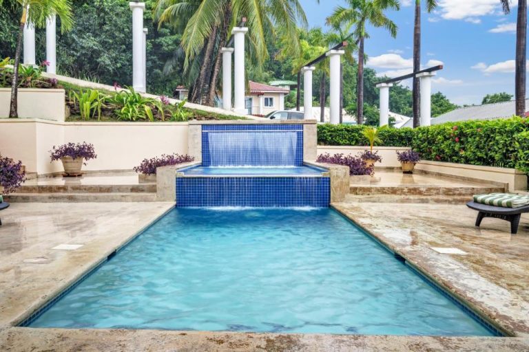 Piscina exterior con cascada de agua y jacuzzi en Sea Vue Luxury Vacation Condominiums rodeada de palmeras