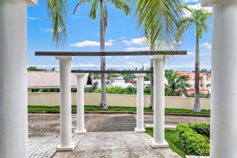 Terraza con columnas blancas y palmeras tropicales en Sea Vue Luxury Vacation Condominiums con vistas al mar