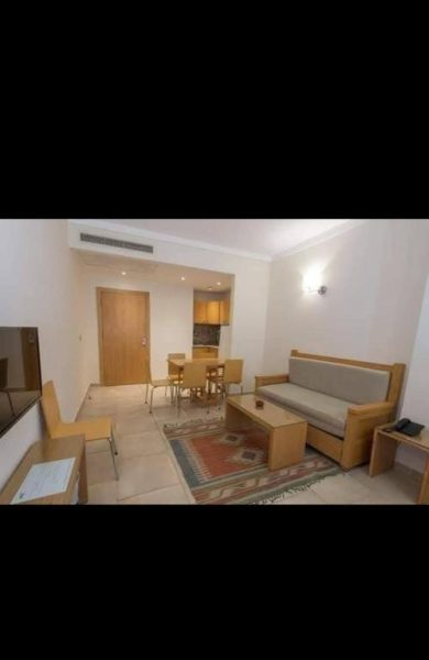 Salón comedor amueblado con sofá y mesa de madera en apartamento de Qaryat Al Dahabia