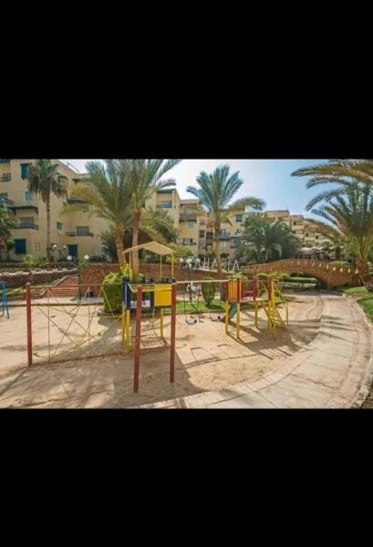 Zona de juegos infantiles con palmeras y edificios residenciales en la Aldahabeya Village Resort