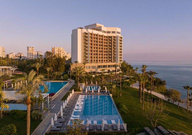 Piscina exterior con tumbonas y jardines tropicales del Akra Antalya con vistas al mar Mediterráneo