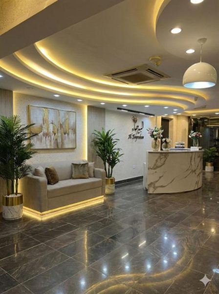 Recepción moderna con mostrador de mármol y elegante lobby iluminado en Al-Bayraha Hotel Apartments