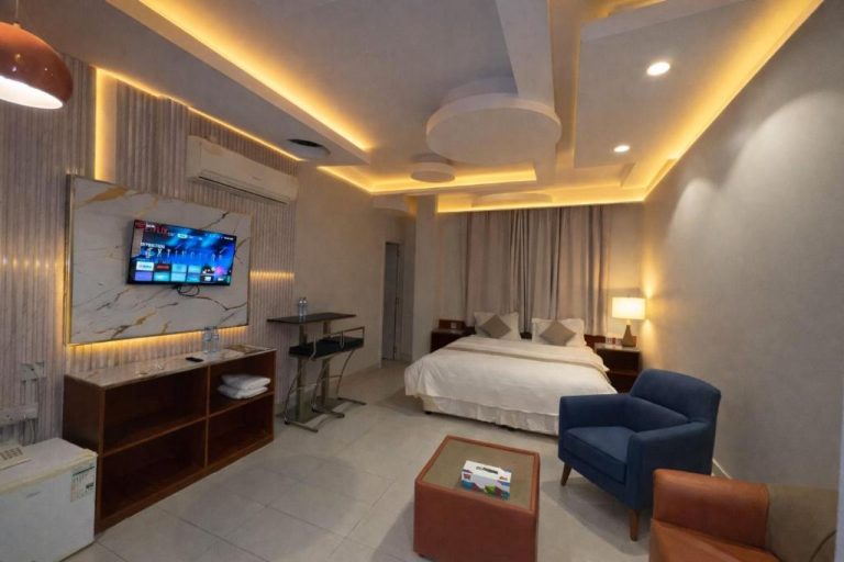 Suite moderna con cama doble, televisor Smart TV y zona de estar en Al-Bayraha Hotel Apartments