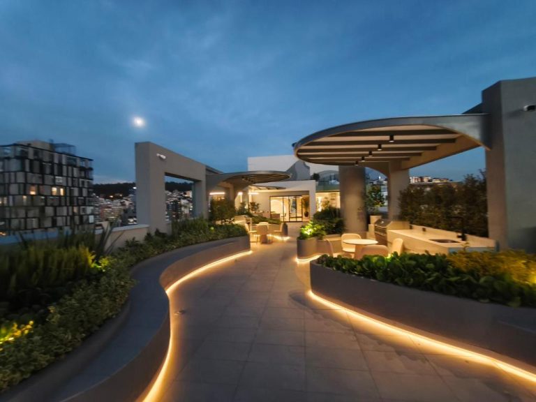 Terraza exterior iluminada con jardines y zona lounge del Adagio Quito Coliving Ecuador Residences