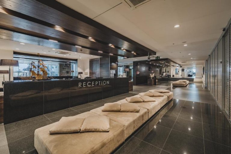 Recepción moderna con mostrador negro y zona de descanso en el Avala Resort & Villas
