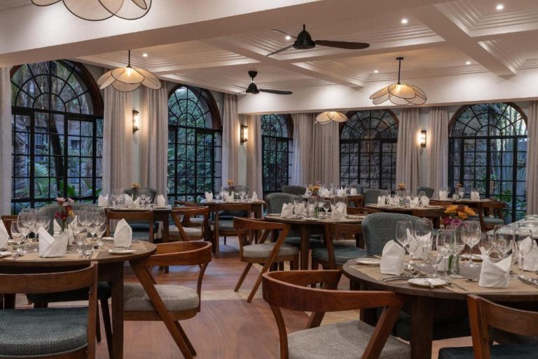 Elegante restaurante del Fairview Hotel Nairobi con mesas vestidas y ventanales arqueados con vistas al jardín