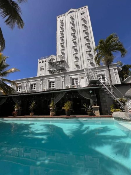 Piscina exterior con agua turquesa y torre principal del Le Saint Georges Hotel rodeado de palmeras