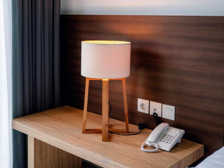 Mesita de noche con lámpara de madera y teléfono en habitación de The Ulu Beach Club and Bungalows