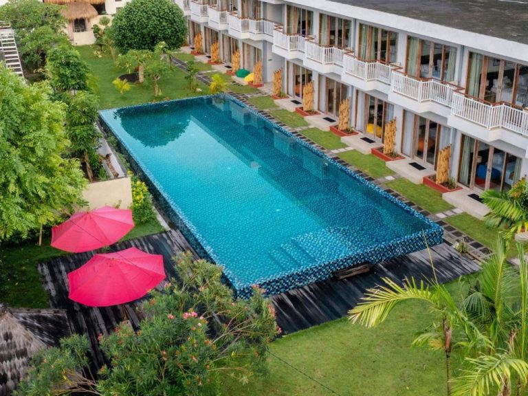 Piscina exterior con mosaico azul y sombrillas rojas en The Ulu Beach Club and Bungalows Bali