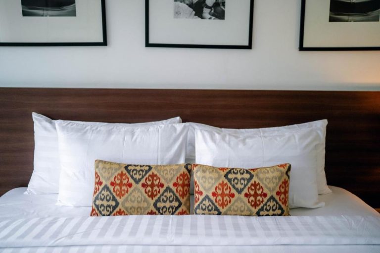 Cama doble con almohadas decorativas en habitación de The Ulu Beach Club and Bungalows