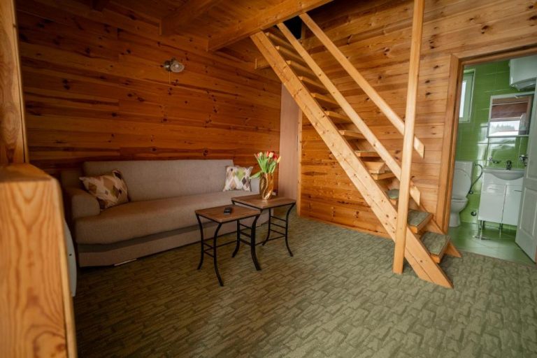 Salón de cabaña de madera con sofá y escalera al piso superior en Hotel Sjever