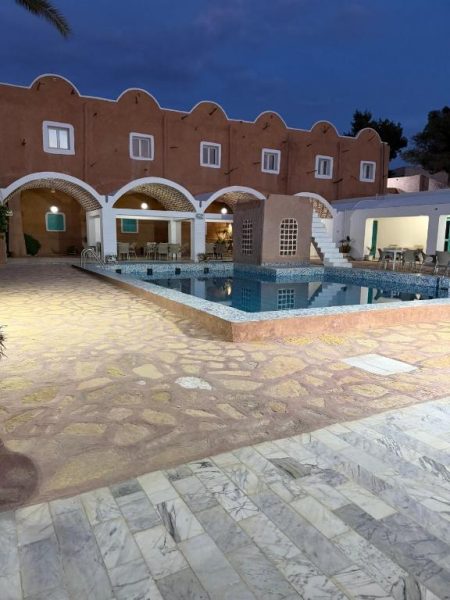 Piscina exterior iluminada del Hotel Matmata con arquitectura tradicional bereber de noche
