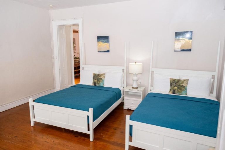 Habitación doble con dos camas individuales de madera blanca y ropa de cama azul en Sweetfield Manor