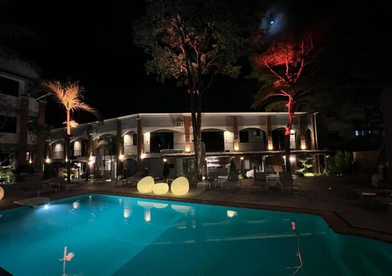 Piscina iluminada de noche con vistas al edificio principal del Aloha Tropicana Samui en Tailandia