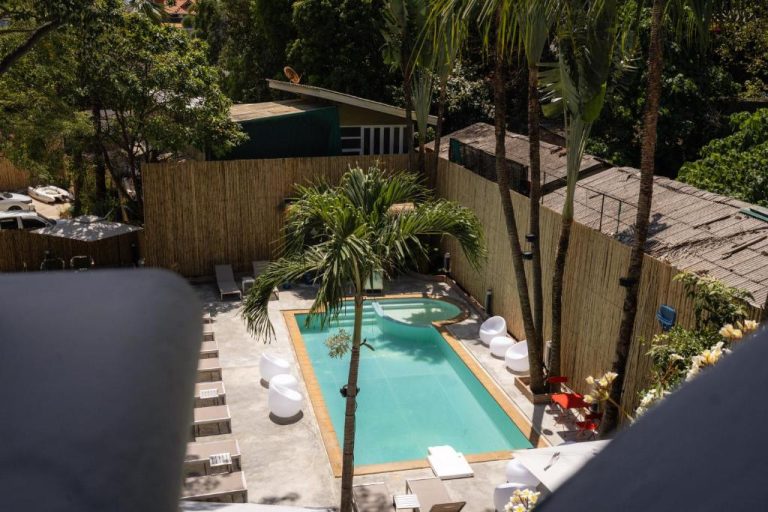 Piscina exterior rodeada de palmeras y tumbonas del Aloha Tropicana Samui en Tailandia