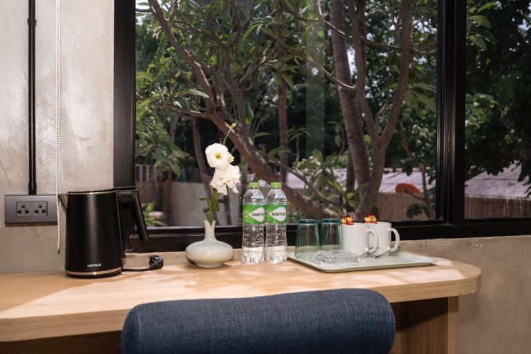 Escritorio con hervidor, botellas de agua Namthip y tazas en habitación del Aloha Tropicana Samui