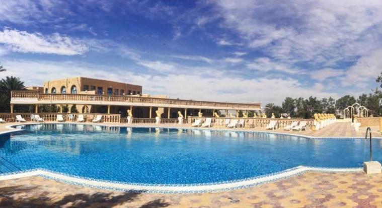 Amplia piscina exterior con tumbonas y arquitectura árabe del Hôtel Jugurtha Palace en Túnez