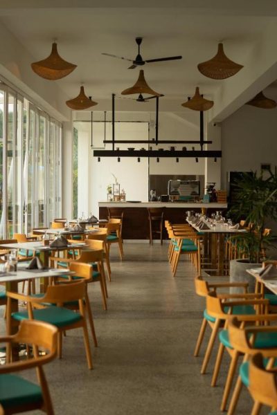 Restaurante interior del Uppuveli Beach by DSK con sillas de madera y lámparas de mimbre
