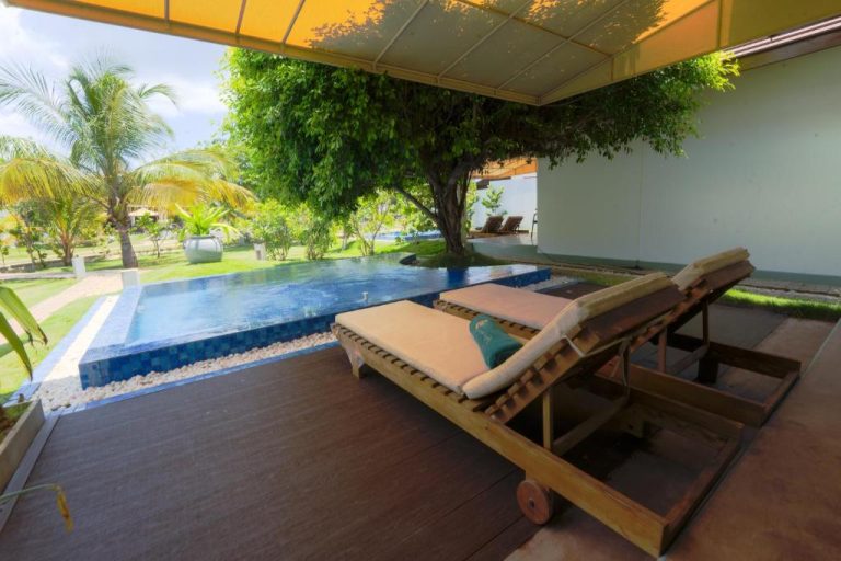 Terraza con tumbonas y piscina privada rodeada de jardín tropical en Uppuveli Beach by DSK