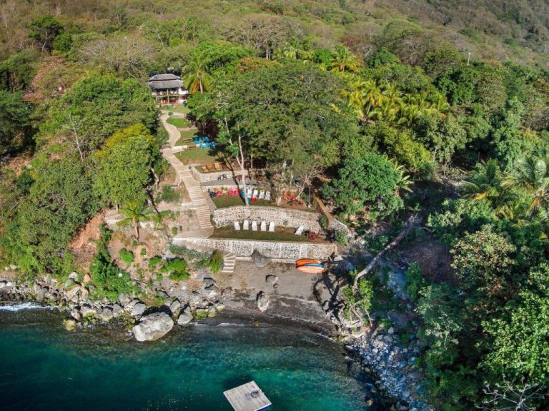 Vista aérea del Laguna Beach Club con acceso privado a playa rocosa, terrazas y jardines tropicales