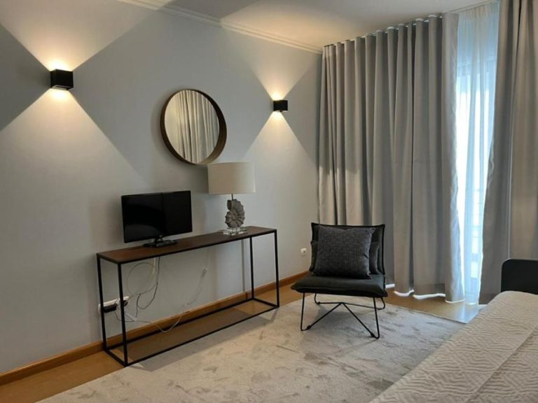 Habitación doble moderna con televisión, sillón y espejo redondo en Hotel do Mar