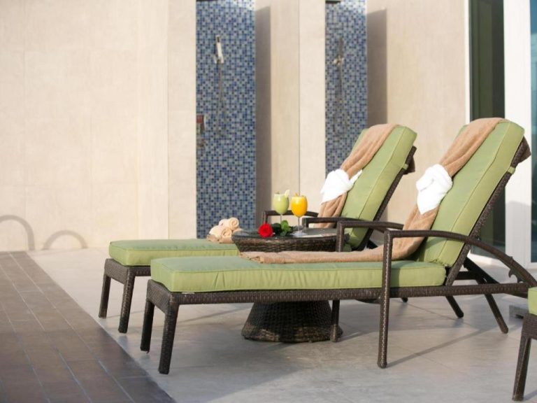 Tumbonas con cojines verdes junto a la piscina del Gulf Pearls Hotel con bebidas y toallas