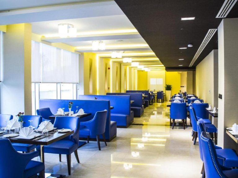 Elegante restaurante del Gulf Pearls Hotel con sillas azules, mesas preparadas y decoración en amarillo y negro