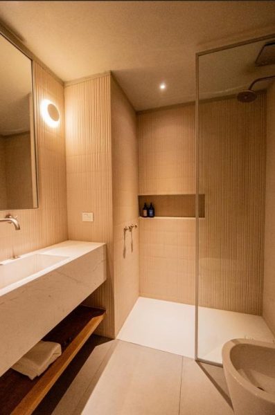 Baño moderno con ducha de cristal y lavabo de mármol blanco en CasaChica Hotel