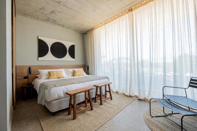 Habitación doble de diseño minimalista con cabecero de madera y arte moderno en CasaChica Hotel