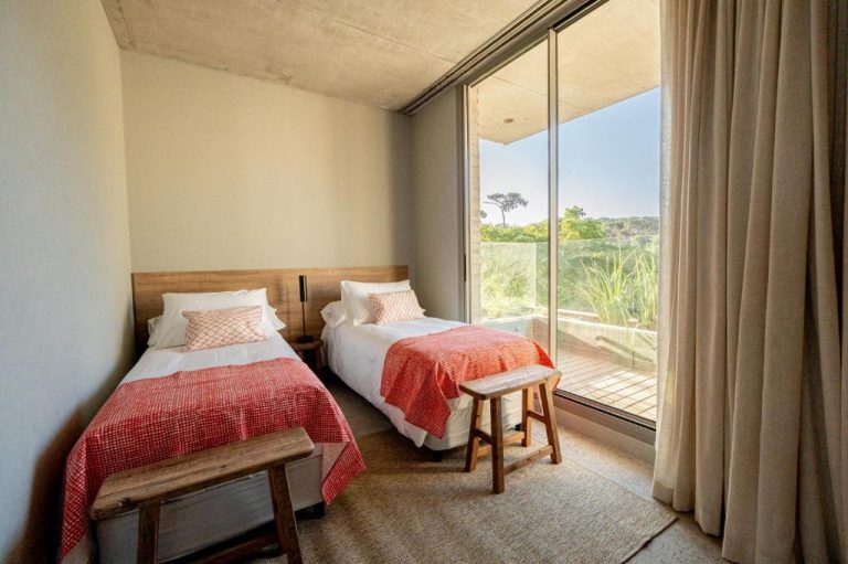 Habitación twin con mantas rojas y terraza con vistas a la naturaleza en CasaChica Hotel