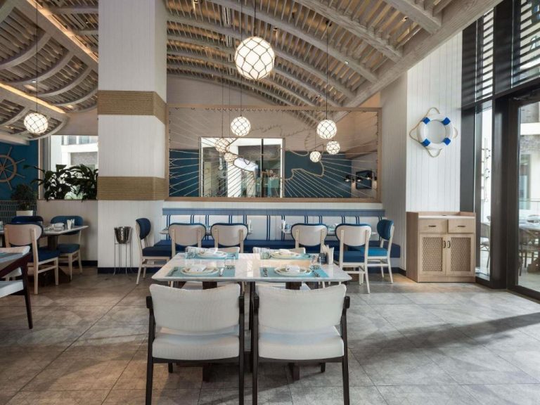 Restaurante de decoración náutica con mesas y sillas en el Alwadi Hotel Doha MGallery Collection