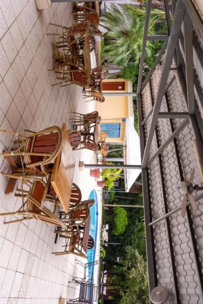 Terraza exterior con mesas y sillas de madera junto a la piscina del Best Western Las Mercedes Airport