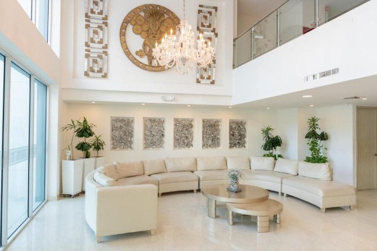 Lujoso lobby del Hotel Tayrona del Mar con sofás blancos, araña de cristal y decoración elegante