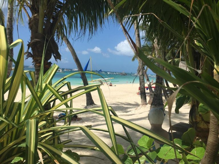 Playa de arena blanca con palmeras y aguas turquesas frente a Sundown Beach Studios en Boracay