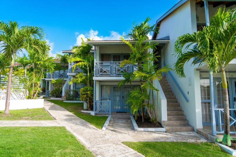 Exterior con jardines tropicales y balcones del Sunset Lane Apartment Hotel en el Caribe